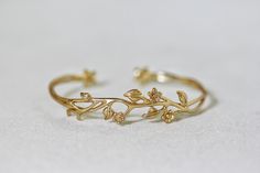 This dainty and beautiful floral bracelet is made out of some entwined branches, a few tiny little flowers and some leaves. This piece is flexible and easy to adjust. It has two tiny flowers sealing each side of the open part, which means you could wear it either facing up or down. * Comes wrapped in a beautiful gift package. * Could be worn on both sides, facing up or down. * Could be requested in either 14k gold, rose gold or silver plated brass. For updates, new products, one-of-a-kind's, spe Gold Flower Bracelet, Branch Bracelet, خواتم خطوبة, Bridal Necklace Designs, Vine Ring, Silver Flower Ring, Flowers Jewelry, Ankle Jewelry, Floral Bracelet