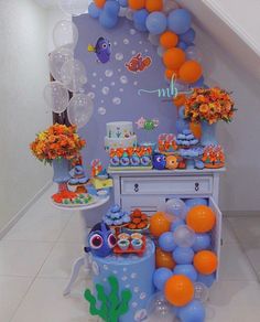 an under the sea themed birthday party with balloons, cake and cupcakes on display