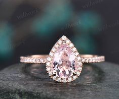 an engagement ring with a pear shaped morganite surrounded by white diamonds on a rock