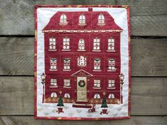 a red and white quilted house with trees on the front, surrounded by wood planks