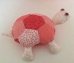 a red and white stuffed turtle sitting on top of a table