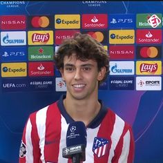 a young man holding a microphone in front of a wall with several different logos on it