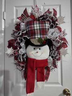 a christmas wreath with a snowman wearing a hat and scarf hanging on the front door