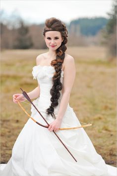 a woman in a white dress is holding an arrow and wearing a long, braided hairstyle