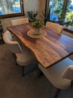 a dining room table with chairs and a potted plant in the center on top