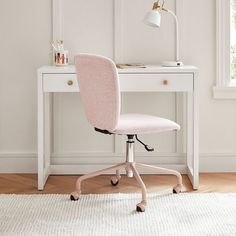 a pink office chair sits in front of a white desk with a lamp on it