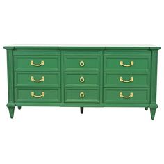 a green dresser with gold handles and drawers on the bottom, against a white background