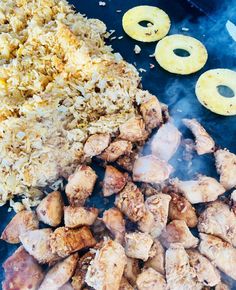 chicken, rice and pineapples are being cooked on an outdoor bbq grill