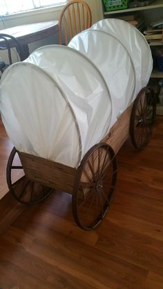 two covered wagons sitting on top of a hard wood floor next to a table and chairs