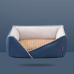 a dog bed with a blue and white cover on it's side, in front of a gray background