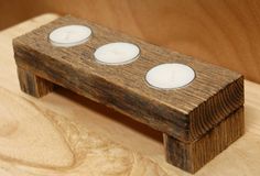 three white candles sitting on top of a wooden stand