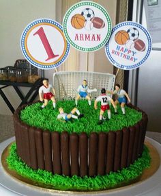 a birthday cake with soccer themed decorations on the top and green grass in front of it