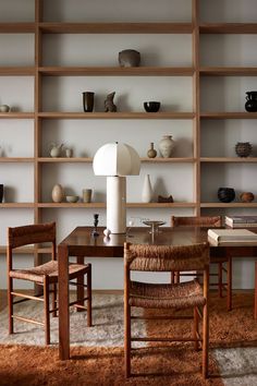 a dining room table with chairs and shelves in the background