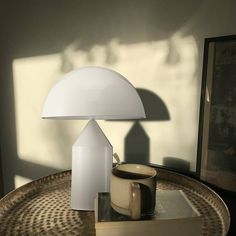 a white lamp sitting on top of a table next to a book and cup filled with coffee