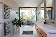 a bathroom with two sinks and a large mirror in it's center, next to a potted plant