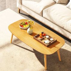 a coffee table with two bowls of fruit on it in front of a white couch