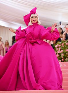 lady in pink dress standing on steps with her arms spread out and hands outstretched to the side