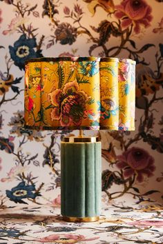 a table lamp that is on top of a floral wallpapered surface with three shades of green and yellow