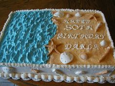 there is a cake that has been decorated with shells and sand on the beach for someone's 50th birthday