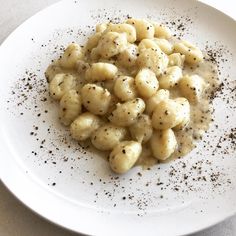 a white plate topped with macaroni and cheese covered in seasoning on top of a table