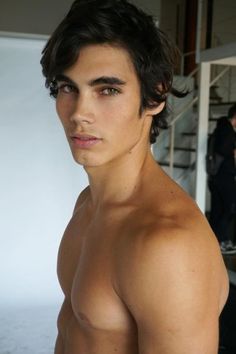 a shirtless young man with no shirt standing in front of some stairs and looking at the camera