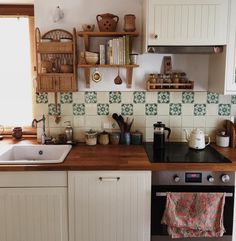 a kitchen with white cabinets and green tile backsplash, wood counter tops, and open shelving