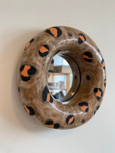 a circular mirror mounted to the wall with leopard print on it's sides and an orange, black, and white design