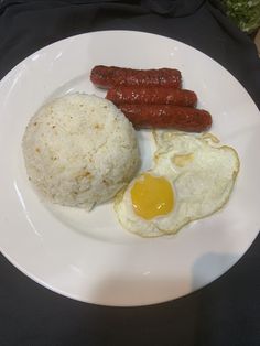 a white plate topped with rice and sausage next to an egg on top of it