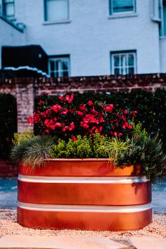 a large metal planter filled with red flowers