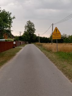 an empty road with a yellow sign on the side and trees in the back ground