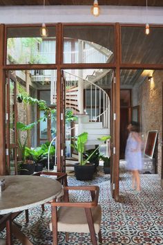 a woman is walking through an open door to a room filled with potted plants