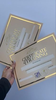 two certificates being held up in the air by someone's hand with their fingers