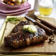 a steak is on a cutting board next to other food and utensils, along with a glass of orange juice