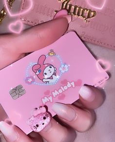 a person holding a pink hello kitty credit card in their hand with hearts on it