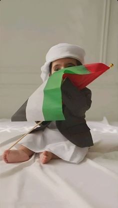 a baby is sitting on the bed holding a flag