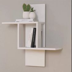 a white shelf with some books and a potted plant sitting on top of it