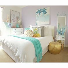 a white bed sitting next to a window with blue and yellow decor on it's sides