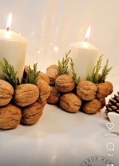 three candles are sitting next to some nuts and pineconuts with greenery on them