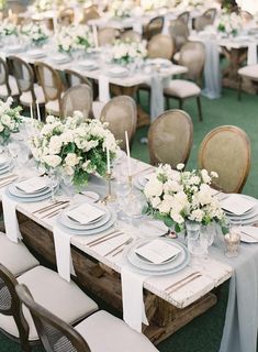 a table set up with white flowers and place settings