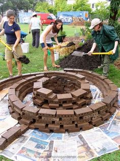 several people are working in the garden with bricks and shovels to build a circular structure