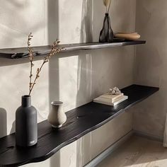 three vases are sitting on a black shelf