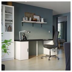 a desk with a computer on top of it in front of a bookshelf