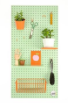 there is a green peg board with plants on it and scissors hanging from the hooks