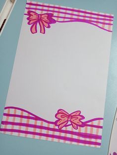 a piece of paper with pink bows on it sitting on top of a blue table