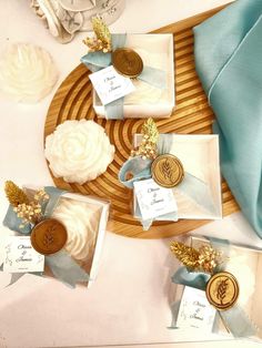 some white and blue items are sitting on a table with gold accents, ribbons and tags