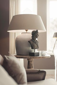 a lamp sitting on top of a wooden table next to a white couch in a living room