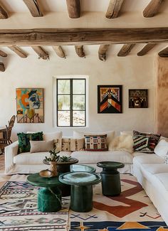 a living room filled with lots of furniture and paintings on the wall above it's windows