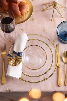 a table set with gold and blue plates, silverware, napkins and wine glasses