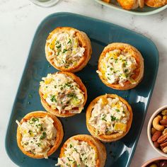 several small appetizers on a blue plate with nuts and other food in bowls