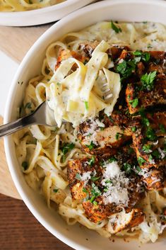 two bowls filled with pasta and meat covered in parmesan cheese, garnished with parsley